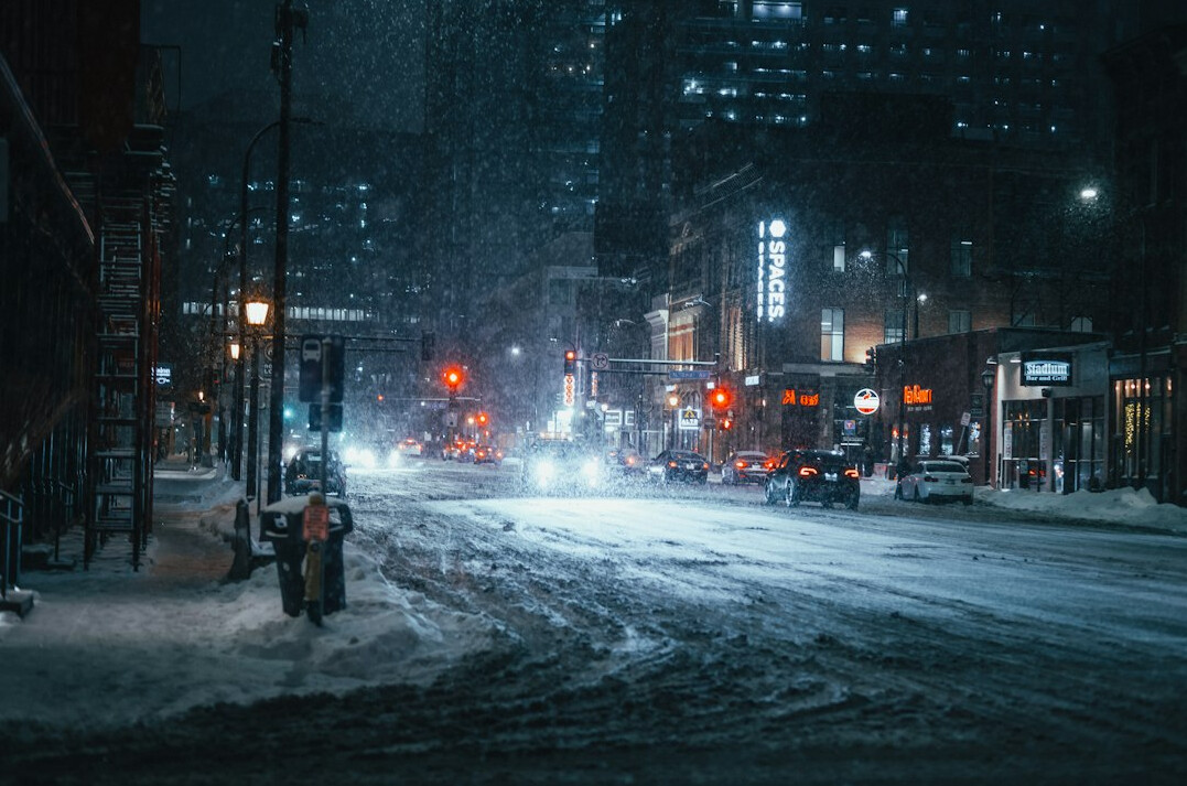 Snow covered residential street in a Canadian city at dawn with warm streetlights
